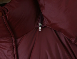 Gros plan sur la fermeture éclair en métal argenté et le matelassage du manteau bordeaux