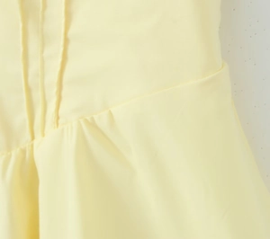 Détail de la robe moulante jaune pâle montrant les coutures en biais et les plis