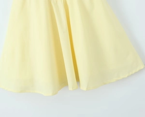 Détail de l'ourlet de robe jaune clair avec mousseline plissée et drapé fluide naturel