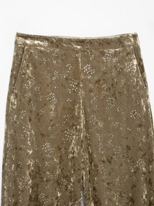 Detail of velvet trousers in olive green with silver floral patterns and high-waist pockets