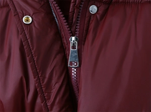 Détail d'une doudoune bordeaux montrant le tissu brillant, le zip et le bouton pression