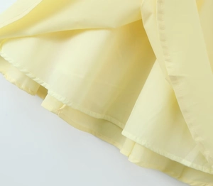 Gros plan détaillé de l'ourlet de robe jaune clair avec coutures et doublure douce