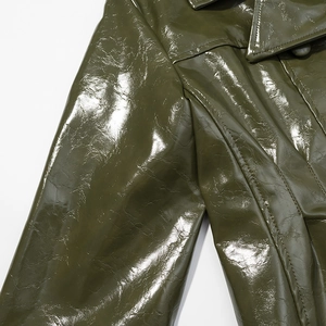 Detail of dark olive green patent leather jacket showing premium stitching and glossy texture