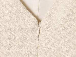 Detail of V-neckline and invisible zipper on a cream white tweed slim dress