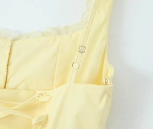 Détail de robe jaune clair avec bordure en dentelle, bretelles réglables et dos lacé
