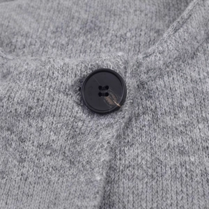 Close-up of grey knit cardigan sweater featuring a marbled black button and wool texture