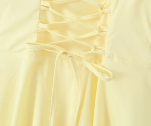 Détail du laçage croisé au dos avec un nœud sur une robe moulante jaune pâle