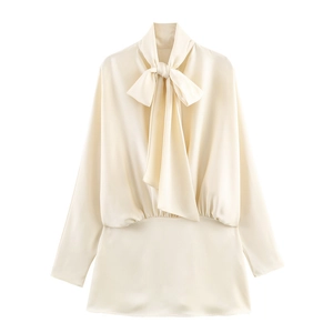 Detail of elegant satin mini dress featuring a pussy-bow neck tie and ruched waist