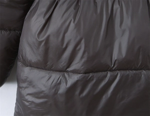 Gros plan du tissu imperméable brillant matelassé et des coutures de la veste d'hiver