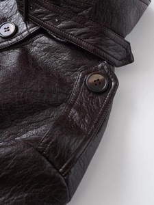 Detail of dark brown faux leather jacket with epaulet button and rich grain texture