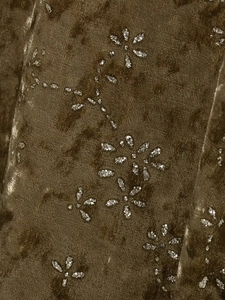 Detailed close-up of moss green velvet fabric featuring shimmering silver floral patterns