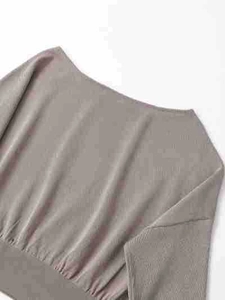 Détail d'un pull en maille taupe montrant l'encolure bateau et l'ourlet côtelé
