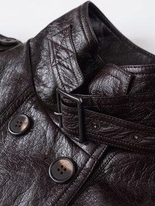 Detailed close-up of dark brown textured PU leather coat with marble resin buttons
