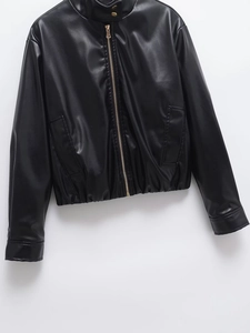 Détail d'une veste en similicuir noir avec col montant et fermeture éclair dorée