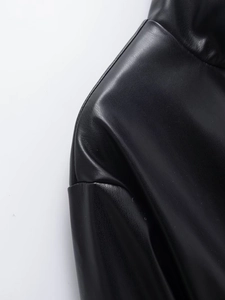 Vue détaillée de la texture du cuir PU noir et des coutures de l'épaule de la veste femme