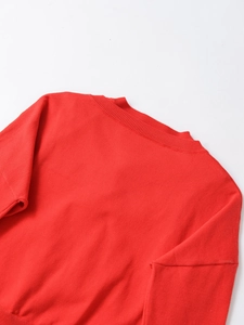 Close-up of the red knitted fabric texture and ribbed crew neck on the casual top