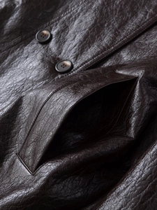 Detail of dark brown faux leather jacket featuring textured grain and round buttons
