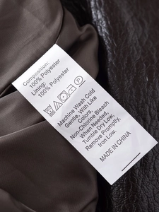 Detail of care label on brown PU leather jacket showing 100% polyester composition