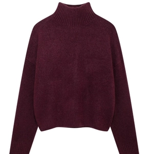 Detailed close-up of burgundy high-neck knit sweater featuring ribbed cuffs and hemline