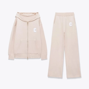 Detail view of beige knit lounge set with C letter patch on hoodie and trousers
