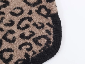 Macro detail of plush leopard print knit fabric with soft texture and black ribbed edge
