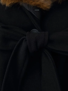 Detail of black wool coat featuring a faux fur collar and waist belt with a bow knot