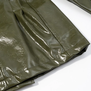 Close-up of olive green patent leather texture and fine stitching on a trendy outfit