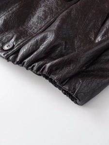 Macro detail of dark brown faux leather jacket sleeve with elastic cuff and button