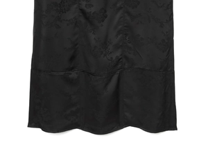 Détail du tissu en satin noir avec motifs jacquard floraux et coutures verticales fines
