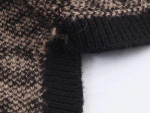 Detail view of jacquard knit texture and ribbed black cuff on a patterned cardigan