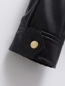 Détail du poignet d'une veste en similicuir noir avec bouton doré et coutures de qualité