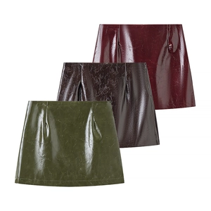 Detailed view of three glossy A-line leather mini skirts in green, brown, and burgundy