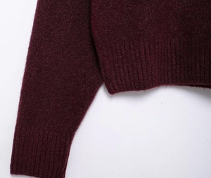Close-up of ribbed cuffs and hem on a plush burgundy knit turtleneck sweater