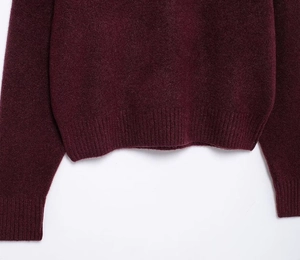 Detail of ribbed hem and cuffs on dark burgundy knit sweater with soft texture