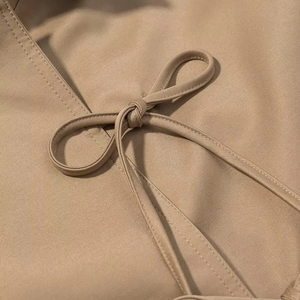 Detail of khaki jacket showing high-quality drawstring bow tie and neat stitching texture