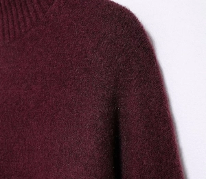 Detailed close-up of soft ribbed knit texture and turtleneck collar in deep wine red