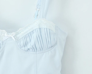 Detail of light blue camisole featuring pleated bust, lace trim, and delicate white bow