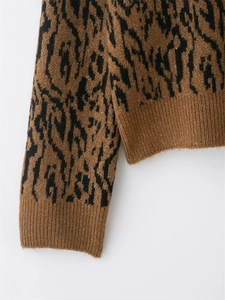 Vue détaillée des poignets côtelés et du motif animal noir sur le pull en maille marron