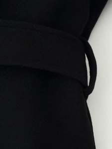 Detailed view of the black wool coat waist area featuring a matching fabric belt and belt loop