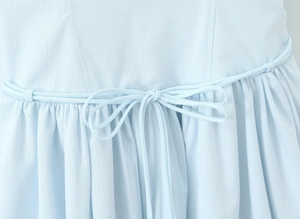 Detail of light blue dress showing textured fabric and delicate drawstring waist bow