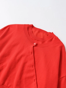 Detail view of red knitted sweater neckline with ribbed texture and matching button closure