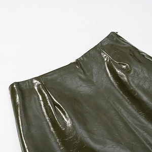 Detail of dark olive faux leather skirt with glossy embossed texture and side zipper
