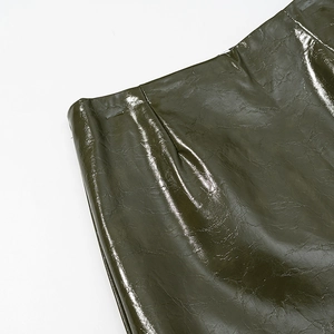 Close-up of dark green glossy patent leather texture and neat stitching on skirt