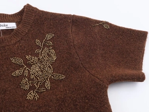 Close-up of brown knit sweater with detailed bead-embroidered floral patterns on collar