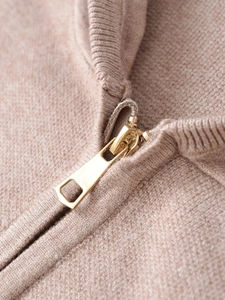 Close-up of golden metal zipper and ribbed knit collar on beige hooded tracksuit