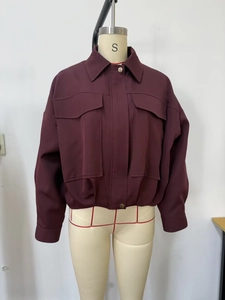 Détail de veste bomber bordeaux avec grandes poches, col à revers et boutons métalliques