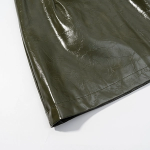Detailed close-up of olive green glossy faux leather texture and precise double stitching