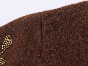 Close-up of deep brown knit sweater featuring golden beaded leaf embroidery details