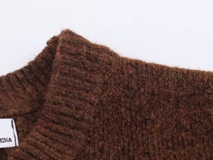 Close-up of dark brown chunky knit sweater showing ribbed neckline and wool texture