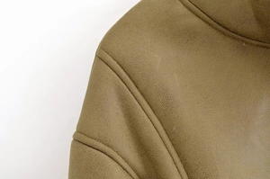 Detailed view of olive green faux suede fabric with precise stitching and matte texture